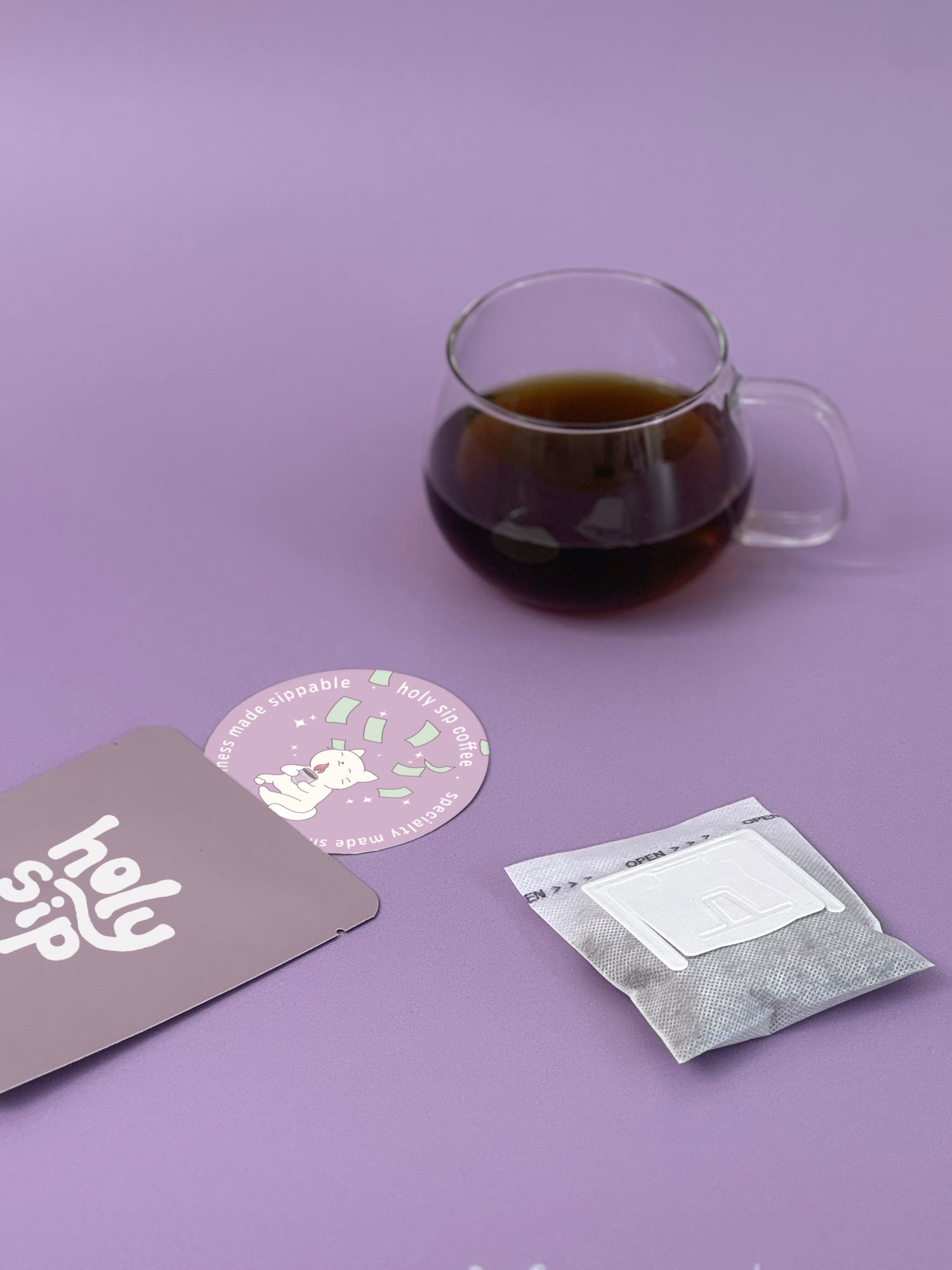 Product photo of holy sip drip coffee bag and coaster with a cup of coffee